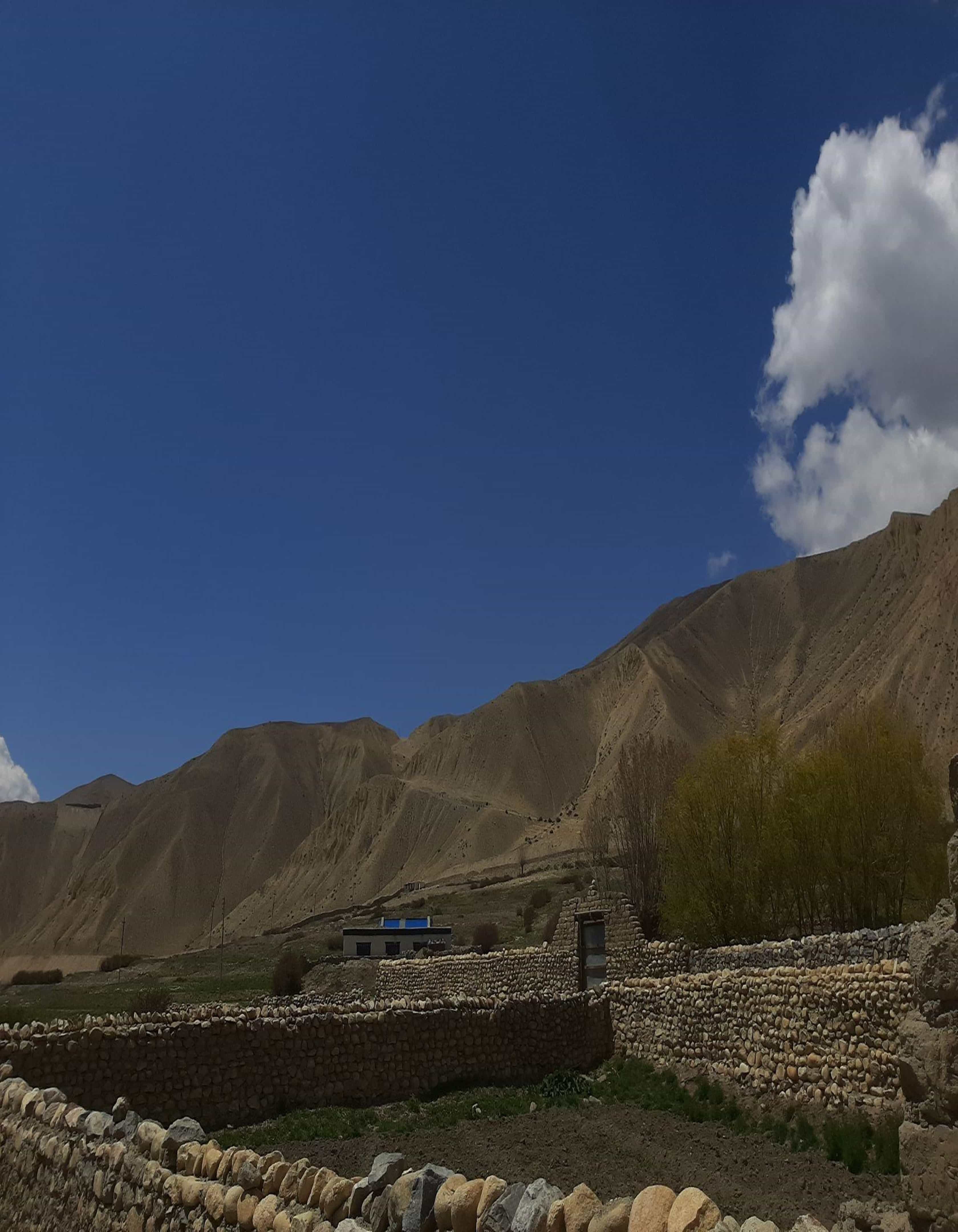 The arid and rugged view from the village of Ghami, with stoned walls and apple farms below the ridge